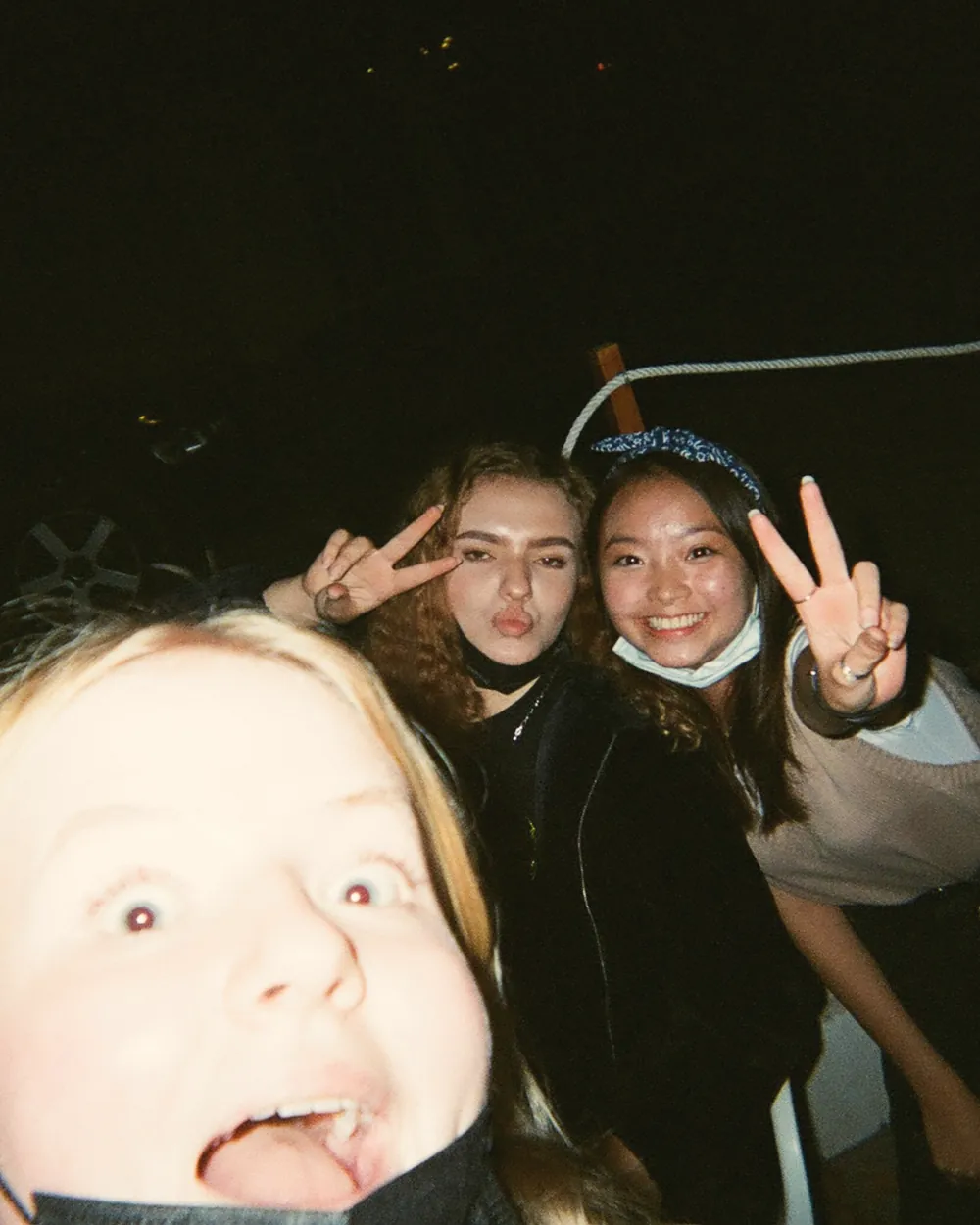Three friends pulling faces at a disposable camera